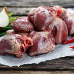 Raw Lamb Hearts on crumpled paper, decorated with vegetables. on